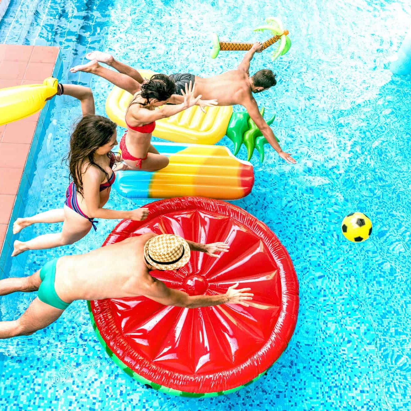 High angle view of millenial friends jumping at swimming pool party - Youth vacation concept with happy guys and girls having fun in summer day at luxury resort - Young people on warm bright filter