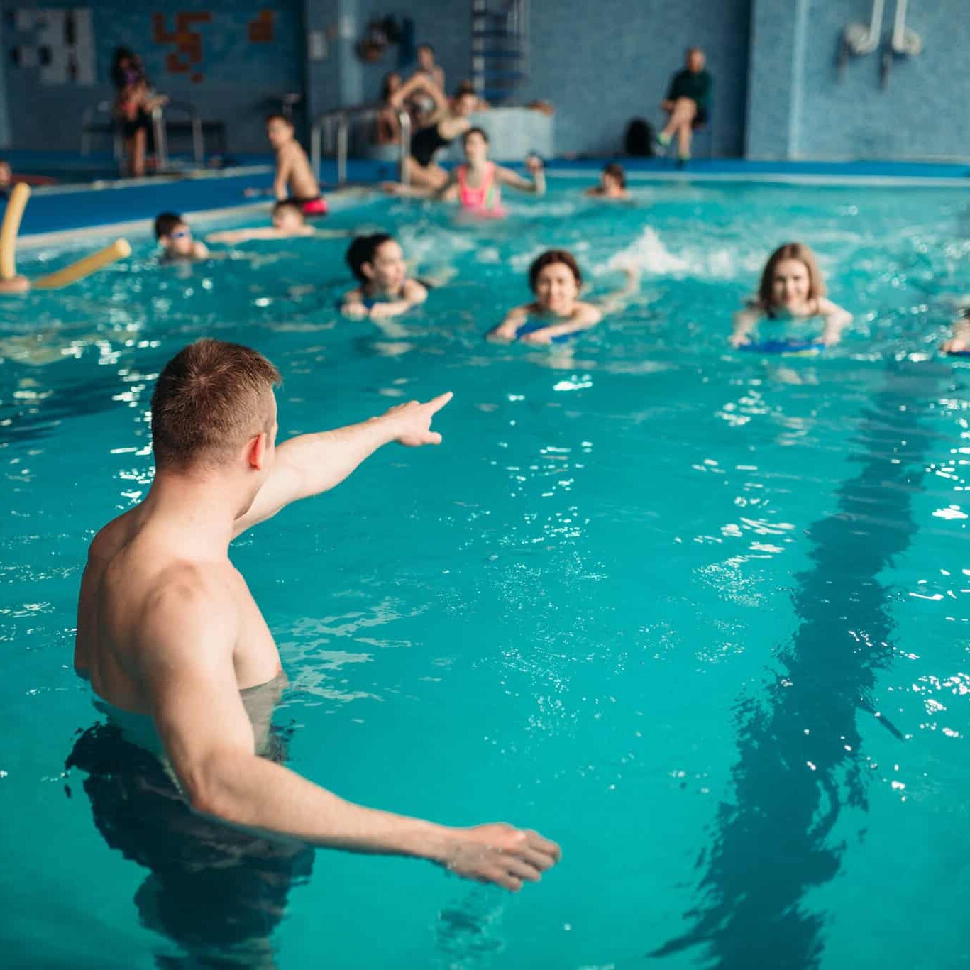instructor works with class in swimming pool instructor works with class in swimming pool
