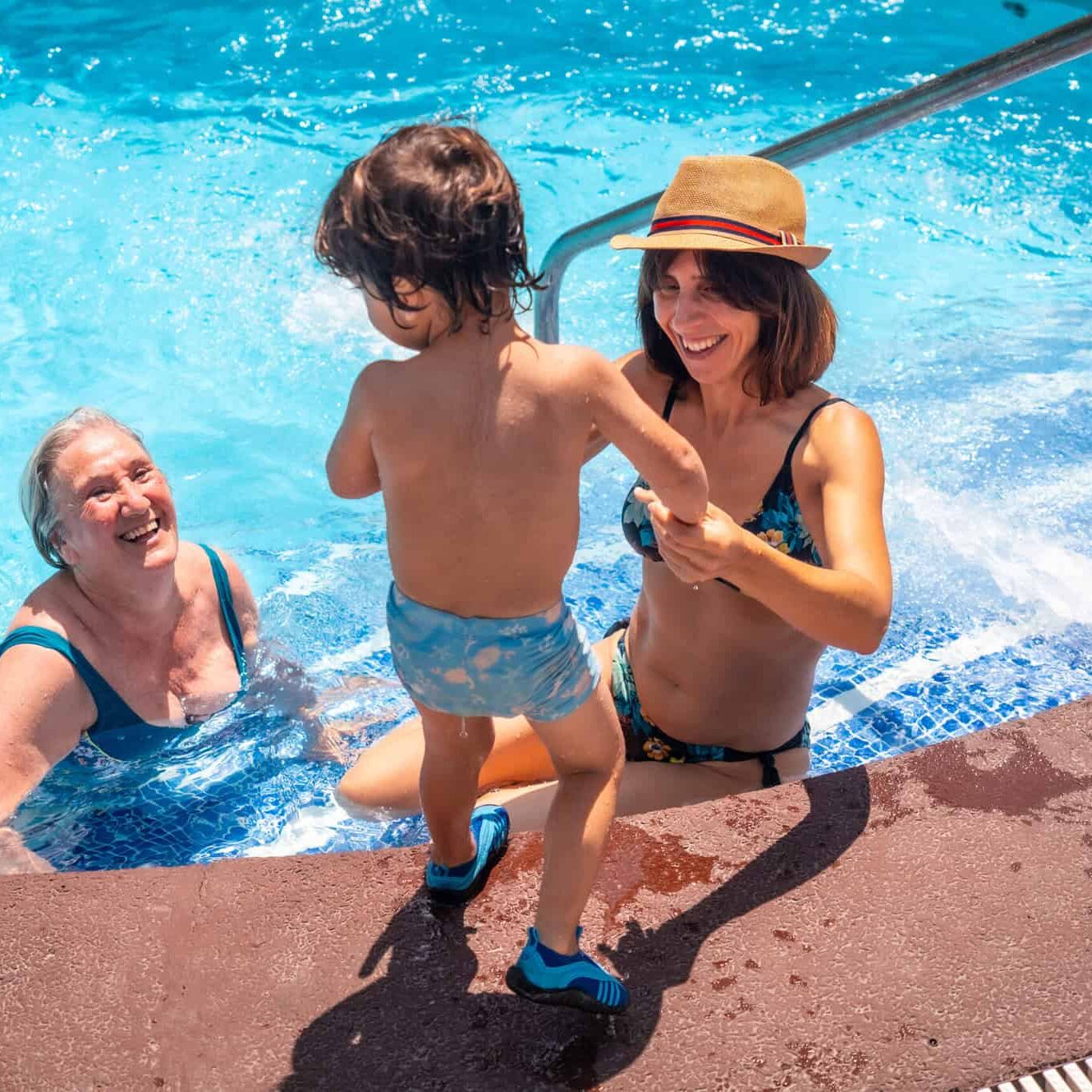 mother and grandmother having fun with grandson in swimming pool on summer vacation, enjoying the water mother and grandmother having fun with grandson in swimming pool on summer vacation, enjoying the water