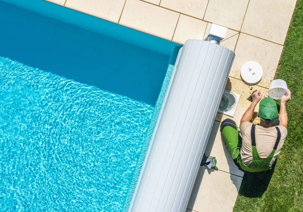Outdoor Backyard Garden Swimming Pool Maintenance. Caucasian Professional Garden SPA Technician Cleaning Skimmer Filter From Dirt. Outdoor Backyard Garden Swimming Pool Maintenance.