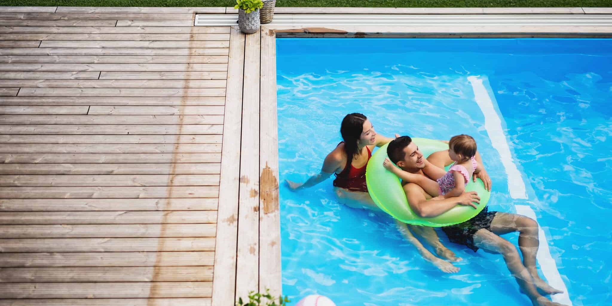 Top view of young family with small daughter in swimming pool outdoors. Top view of young family with small daughter in swimming pool outdoors in backyard garden.